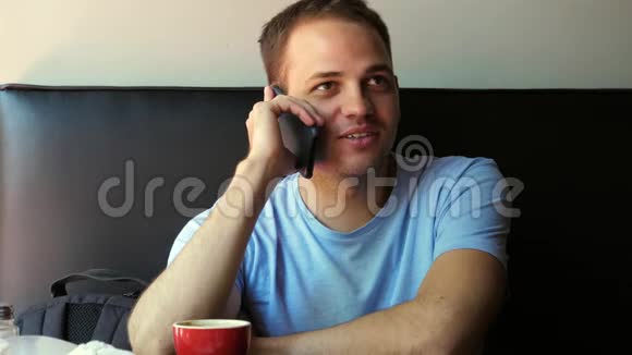 室内拍摄的微笑年轻人坐在手机上交谈在咖啡馆打电话的快乐小伙子视频的预览图