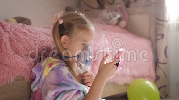 小女孩在家拿着吸入器面罩生病的孩子通过雾化器呼吸婴儿使用治疗哮喘或视频的预览图