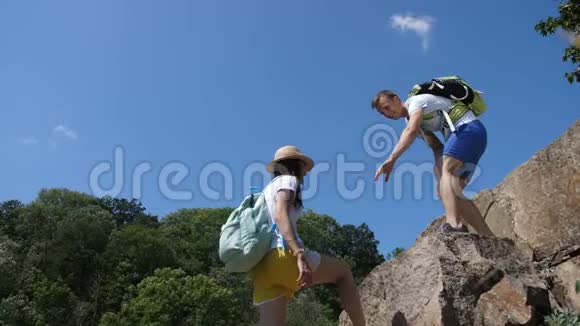 登山男子帮助妇女爬上陡峭的岩石视频的预览图