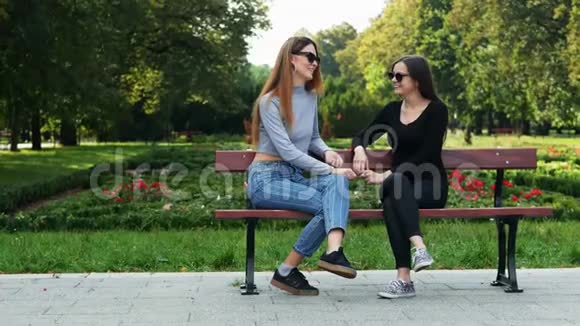 两个女朋友坐在公园里的长凳上聊天视频的预览图