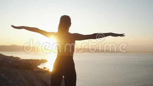 清晨在阳光下做伸展运动的女人剪影视频的预览图