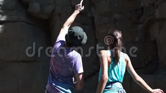 两个登山者男人和女人站在花岗岩崖下有着攀爬的路线看着路线的一部分视频的预览图