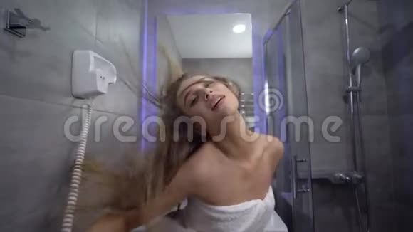 在浴室里一个穿着一条毛巾留着漂亮长发的开朗女孩积极地调情并为相机摆姿势视频的预览图