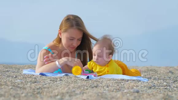 年轻的母亲在沙滩上和她的孩子玩闹视频的预览图