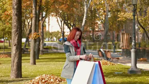 快乐的女孩长着狐狸般的头发穿着五颜六色的纸袋穿过公园感到很高兴视频的预览图