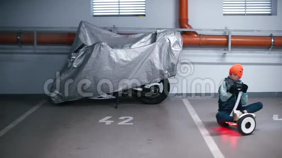 一个男孩坐在一个陀螺仪上骑在地下停车场周围视频的预览图