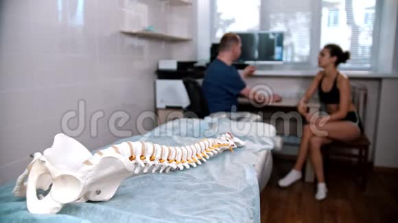 脊椎治疗医生在手术前检查年轻妇女放置在人体脊柱上的模型视频的预览图