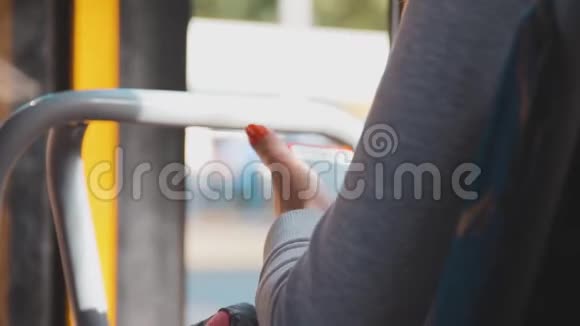 一个穿着浅色针织上衣的女孩手里拿着一部手机在乘客公共汽车停车时使用智能手机一个女人在看视频的预览图