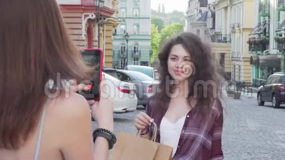一位性格开朗的年轻女士带着购物袋摆姿势为她的朋友拍照视频的预览图