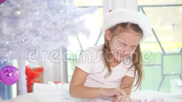 戴着圣诞老人帽子的不开心的哭泣女孩正坐在圣诞树附近抱怨因为她没有得到礼物视频的预览图