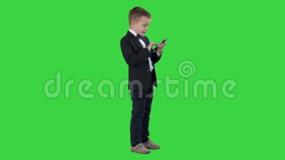年轻的男孩穿着优雅的西装在绿色屏幕上玩手机色度键视频的预览图