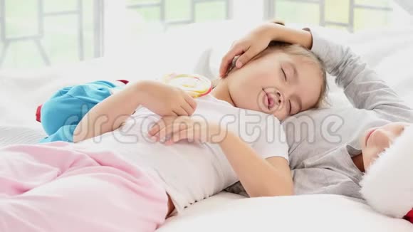 迷人的姐姐正睡在哥哥的肚子上拿着大棒棒糖在棍子上两人看起来都很甜蜜视频的预览图