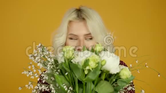 笑着金发女孩拿着花在黄色的背景上跳舞视频的预览图