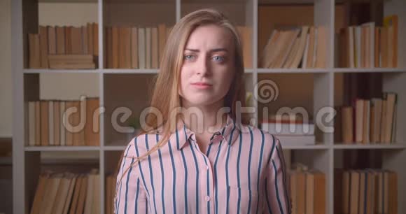 年轻漂亮的白种人女学生在大学图书馆里看镜头时困惑的特写镜头视频的预览图