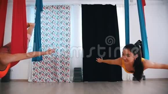 摄影棚里的空中瑜伽两个女人躺在吊床上在里面摇摆视频的预览图