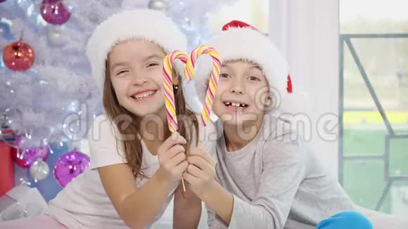 可爱的白种人孩子们享受圣诞节的早晨在床上玩耍用糖果罐头做心脏然后舔条纹视频的预览图
