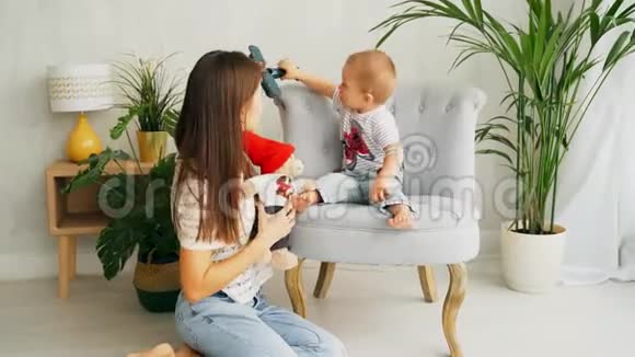 快乐的养母正在和她的小儿子玩一个小男孩坐在扶手椅上视频的预览图