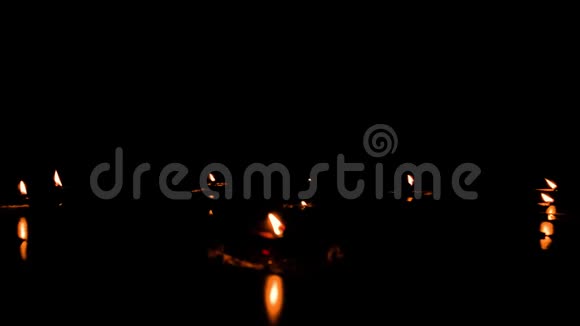 迪娅灯在节日季节的排灯节黑色背景上燃烧油灯的一组在黑暗中点燃蜡烛视频的预览图