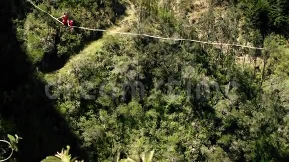 极端男性平衡在斜坡线或紧绳高处与绿色森林和流动的河流背景视频的预览图