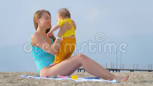 一位年轻的母亲在沙滩上和她的孩子玩耍视频的预览图