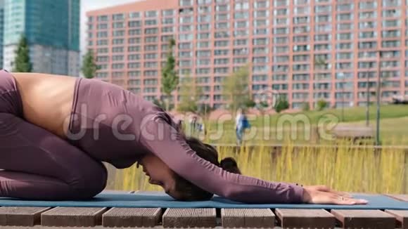 年轻女子做瑜伽运动与城市背景巴拉萨纳视频的预览图