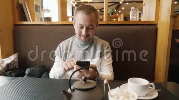 一个拿着手机在咖啡馆里的男人视频的预览图