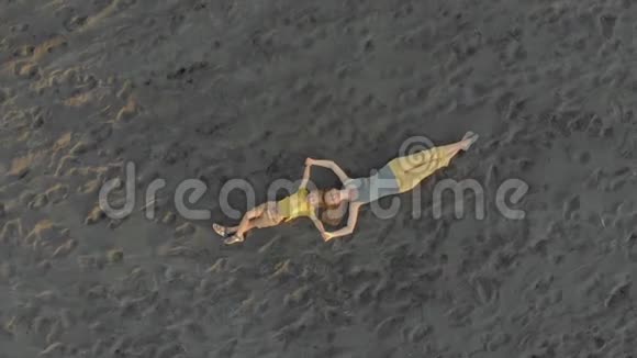一家人的母亲和儿子躺在黑色沙滩上的空中射击视频的预览图