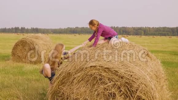 女孩正试图爬上干草堆找朋友坐在上面帮助她视频的预览图
