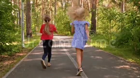 十几岁的女孩朋友在柏油路上的自然公园里玩跑步跳跃视频的预览图