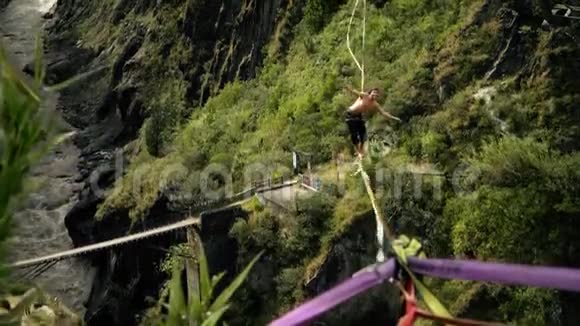 极端男性平衡在斜坡线或紧绳高处与绿色森林和流动的河流背景视频的预览图
