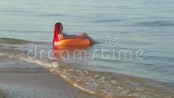 一个穿着泳衣的女人在游泳圈的海面上荡起浪花视频的预览图