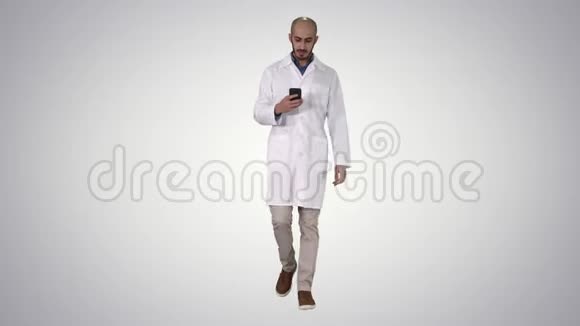 男性阿拉伯医生在渐变背景下行走时在电话上发短信视频的预览图