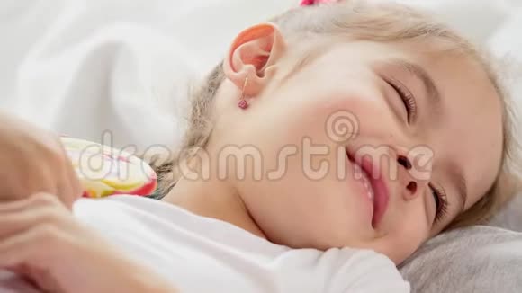 可爱的视频华丽的孩子与有趣的辫子醒来舔红黄色的糖果棒微笑可爱视频的预览图