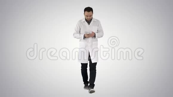 医生在梯度背景下在手机上行走和写信息视频的预览图