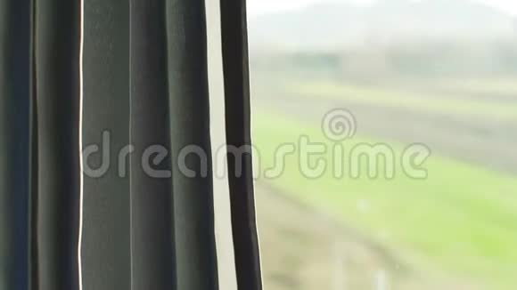 从火车的窗户看阳光照在窗帘的左边模糊的房子和国家后面的玻璃窗格的右边视频的预览图