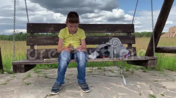 一个十几岁的男孩在用烤香肠从塑料容器里取出一块全麦棕色面包时视频的预览图