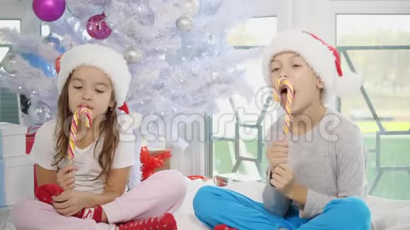 有趣的视频非常兴奋的兄弟姐妹与糖果在牙齿花时间在一起在白色卧室的圣诞节视频的预览图