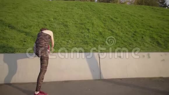 运动妇女伸腿把脚放在水泥栅栏上视频的预览图