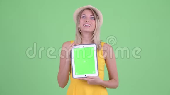 一位年轻的金发碧眼的旅游女伴在讲数字平板电脑视频的预览图