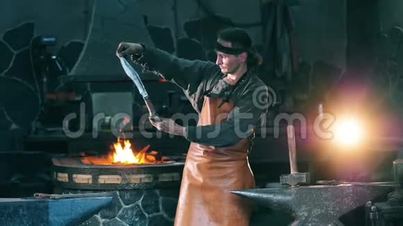 职业铁匠检查一把金属刀站在锻炉前视频的预览图