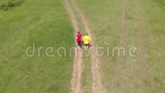 体育少年和她父亲在草地上奔跑空中镜头视频的预览图