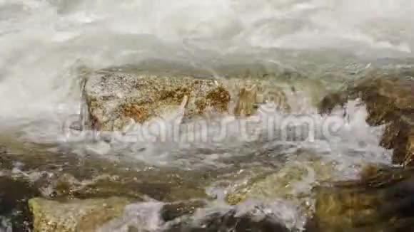 慢动作视频阳光照耀河流中的水流过大岩石形成白色的波浪视频的预览图