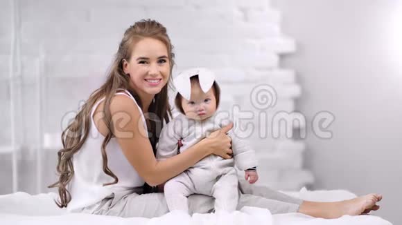 可爱的微笑的年轻母亲坐在床上抱着刚出生的孩子看着摄像机视频的预览图