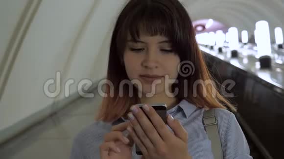 快乐的女人使用智能手机乘自动扶梯到地铁视频的预览图