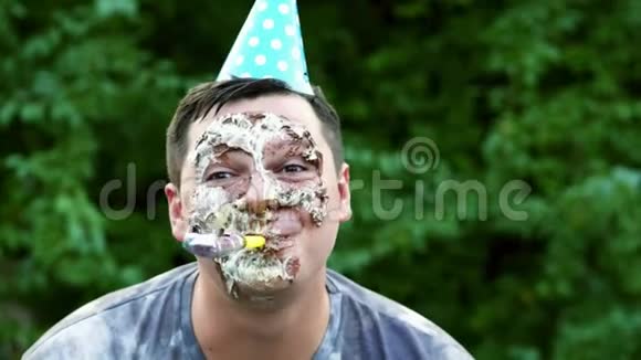 快乐男人的特写镜头面带奶油蛋糕他微笑着风趣地吹着口哨在派对上开着玩笑视频的预览图