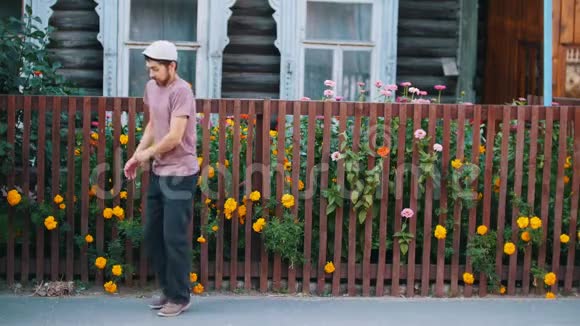 一个戴着白帽子的男人在村子里用鲜花在篱笆旁跳舞视频的预览图