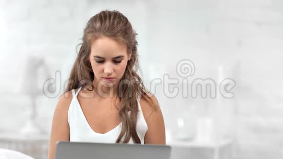自信漂亮的休闲女性在白色房间周围使用笔记本电脑聊天视频的预览图