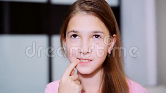 年轻女孩用手指指着一颗缺失的牙齿一个女孩的肖像视频的预览图