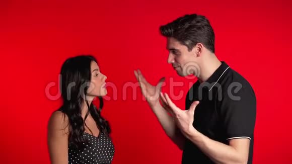 年轻夫妇在演播室的红色背景上激烈争吵冲突的概念关系中的问题视频的预览图