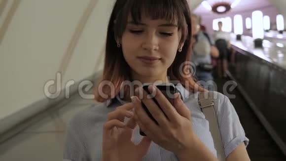 有魅力的女人使用智能手机乘自动扶梯到地铁视频的预览图